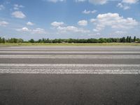 a man riding his motorcycle down an empty road near green grass and shrubs in the background