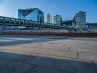 a skateboarder riding on a cement ramp next to a city street under a bridge