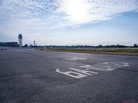 an empty runway with a sign on it and some trees in the background on top of the runway