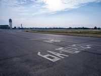 an empty runway with a sign on it and some trees in the background on top of the runway