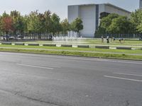 a person rides his bike down the road in front of a water fountain with statues on each side