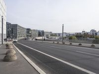 two empty, narrow roads in front of a city skyline with parked cars and pedestrians