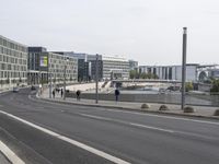 two empty, narrow roads in front of a city skyline with parked cars and pedestrians