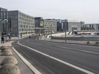 two empty, narrow roads in front of a city skyline with parked cars and pedestrians