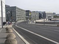 two empty, narrow roads in front of a city skyline with parked cars and pedestrians