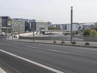 two empty, narrow roads in front of a city skyline with parked cars and pedestrians