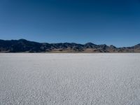 the sky is blue and clear above a large desert plain with mountains in the distance