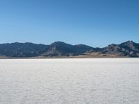 the sky is blue and clear above a large desert plain with mountains in the distance