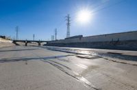 a man riding down the middle of a road on a skateboard near water and power lines