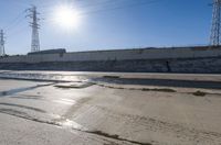 a man riding down the middle of a road on a skateboard near water and power lines