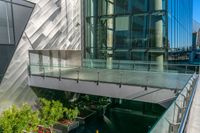 a glass balcony in front of a modern building overlooking the city streets and buildings through which there is trees