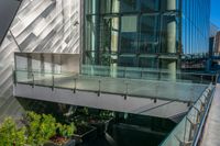 a glass balcony in front of a modern building overlooking the city streets and buildings through which there is trees