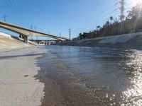 an empty road and street in front of an overpass of a bridge with water going under it