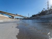 an empty road and street in front of an overpass of a bridge with water going under it