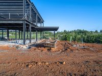 a picture of a building being built on a field near a forest in the background