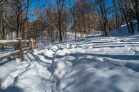 a snowy path in the woods with lots of snow on the ground and a wooden railing