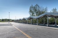 bus stop next to empty parking lot with trees and fence in the background and clear blue skies in the background