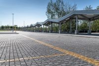 bus stop next to empty parking lot with trees and fence in the background and clear blue skies in the background