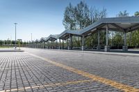 bus stop next to empty parking lot with trees and fence in the background and clear blue skies in the background