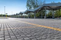 bus stop next to empty parking lot with trees and fence in the background and clear blue skies in the background