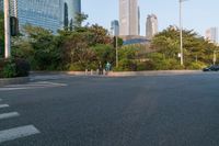 a group of pedestrians crossing the street in front of a city skyline view at sunset