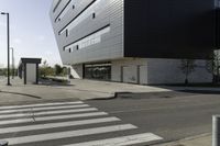 some people are walking across a crosswalk near a large building while two zebra crossing crosses are near