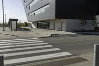 some people are walking across a crosswalk near a large building while two zebra crossing crosses are near