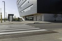 some people are walking across a crosswalk near a large building while two zebra crossing crosses are near