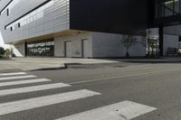 some people are walking across a crosswalk near a large building while two zebra crossing crosses are near