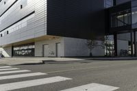 some people are walking across a crosswalk near a large building while two zebra crossing crosses are near