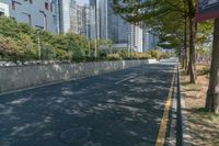 an empty street and a line of tall buildings are visible in this image, a man walks by