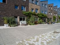 a building on a quiet street with plants in front of it and cars parked on the road