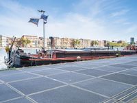 a barge boat is next to a street with buildings in the background at a marina