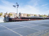 a barge boat is next to a street with buildings in the background at a marina