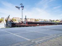 a barge boat is next to a street with buildings in the background at a marina