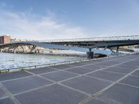 a road leading to a bridge over water surrounded by large buildings with a sky in the background