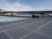 a road leading to a bridge over water surrounded by large buildings with a sky in the background