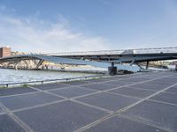 a road leading to a bridge over water surrounded by large buildings with a sky in the background