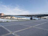 a road leading to a bridge over water surrounded by large buildings with a sky in the background