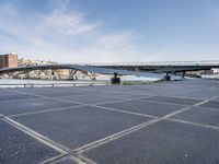 a road leading to a bridge over water surrounded by large buildings with a sky in the background