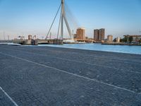 a pedestrian bridge over a river on a sunny day in europe by a city skyline