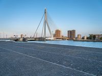 a pedestrian bridge over a river on a sunny day in europe by a city skyline