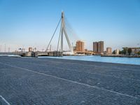 a pedestrian bridge over a river on a sunny day in europe by a city skyline