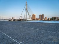 a pedestrian bridge over a river on a sunny day in europe by a city skyline