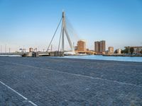 a pedestrian bridge over a river on a sunny day in europe by a city skyline