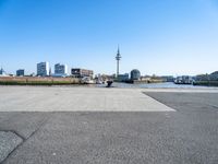 a street with a car parking lot on it with a blue sky and city in the background