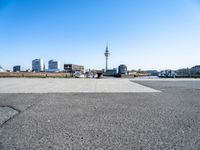 a street with a car parking lot on it with a blue sky and city in the background