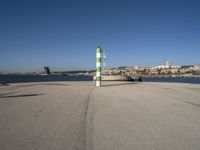 this is an ocean front with the town in the background and a road sign on the end of the walkway