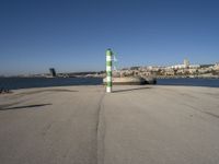 this is an ocean front with the town in the background and a road sign on the end of the walkway