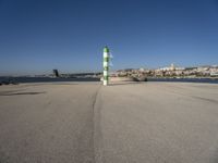 this is an ocean front with the town in the background and a road sign on the end of the walkway